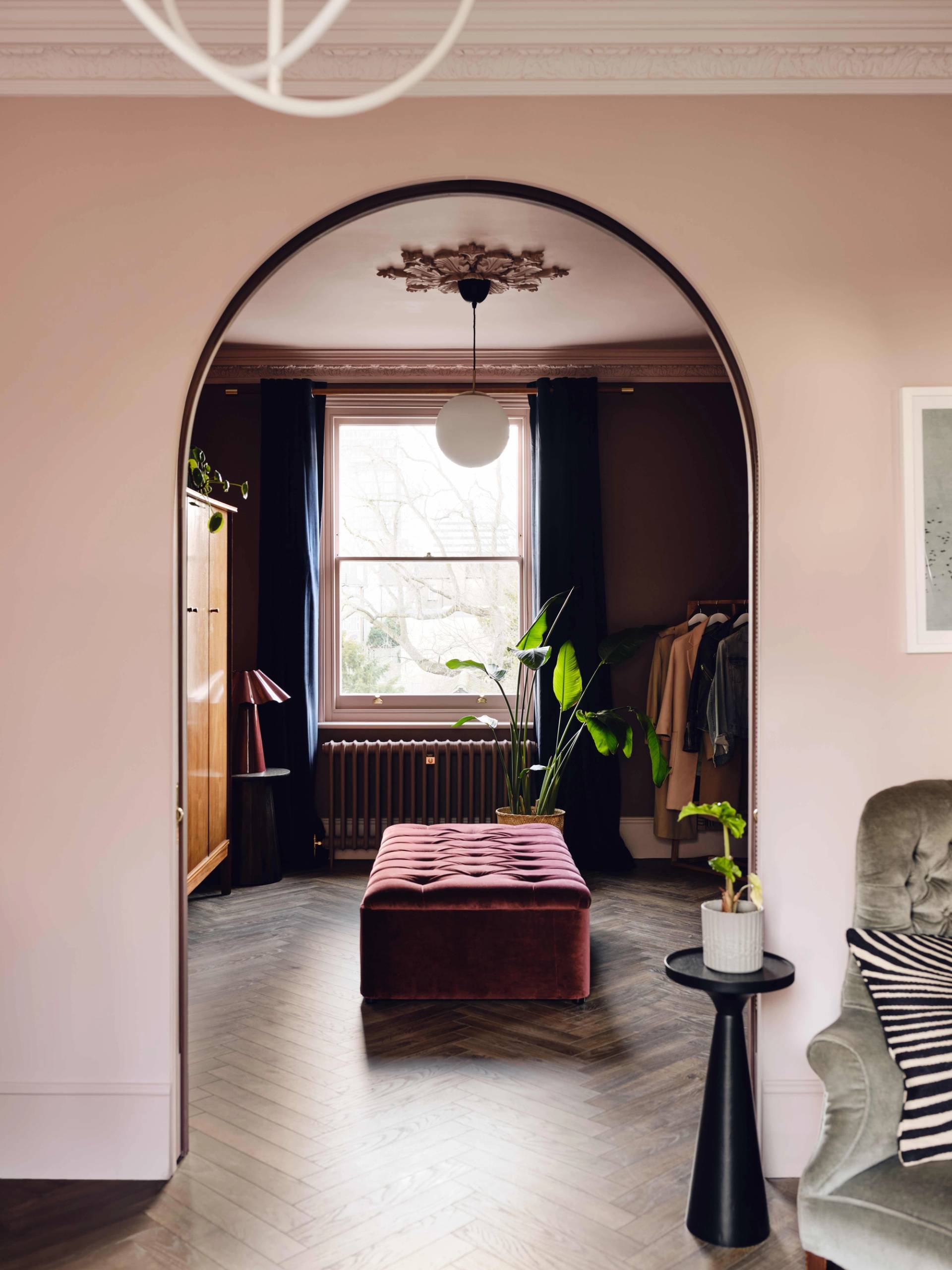 View looking through a plaster archway into a cozy bedroom suite with dark curtains, Love Locations CR0.