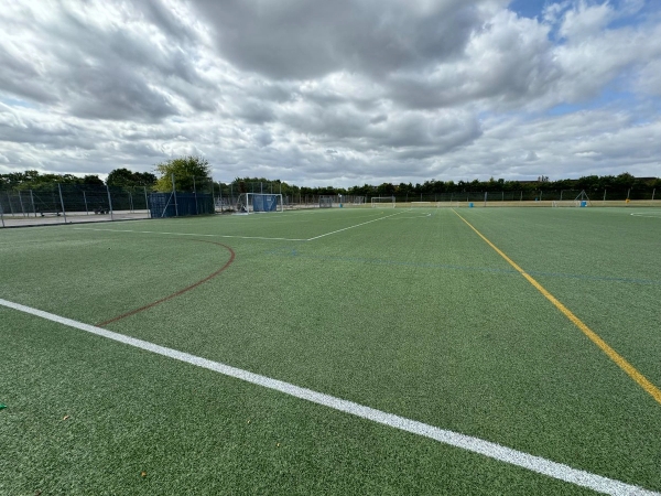 Love Locations school all-weather pitch Cockfosters: Expansive synthetic outdoor playing field bordered by perimeter safety fencing, ideal for sports action sequences and commercial video.