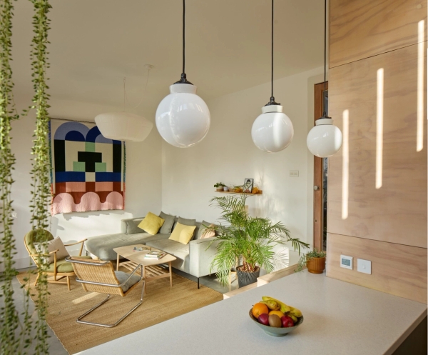 Plywood kitchen island detail with brass taps, pendant lighting, and modern living room furniture, Love Locations E17.