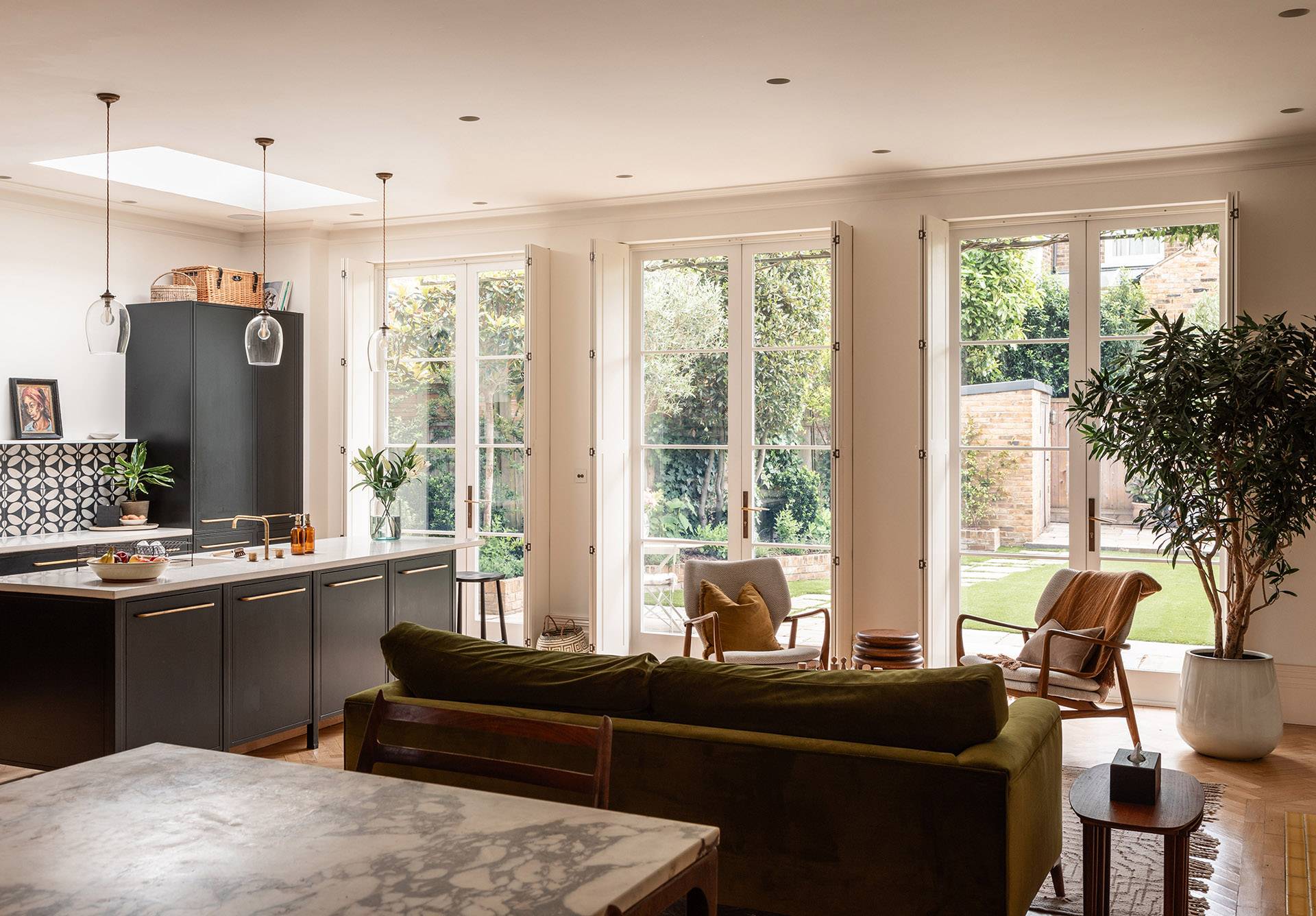 Open-plan living space view looking from the dining zone through glass doors toward the rear terrace, Love Locations.