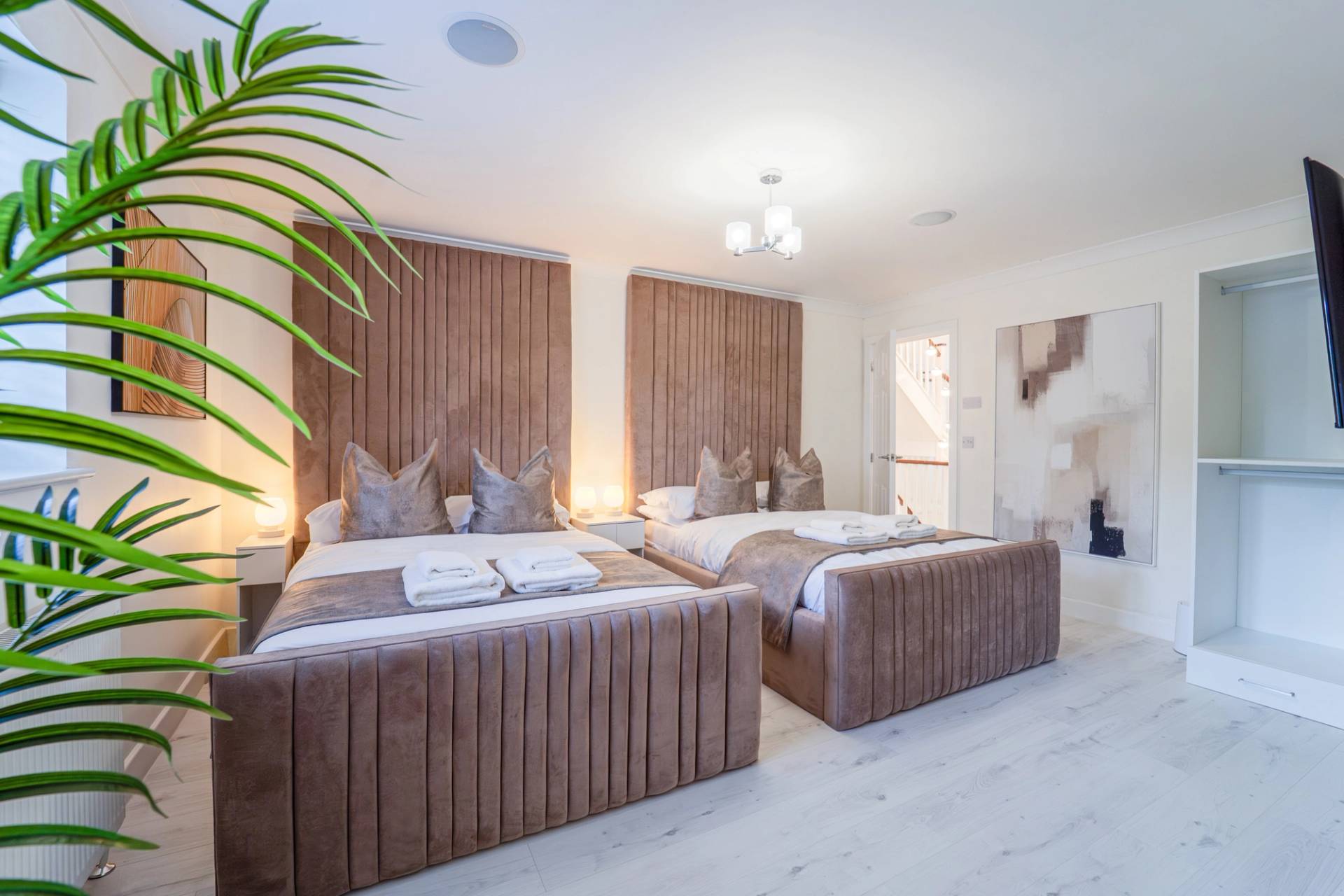 Twin bedroom setup featuring velvet channel-upholstered headboards and light laminate flooring, Love Locations RM11.
