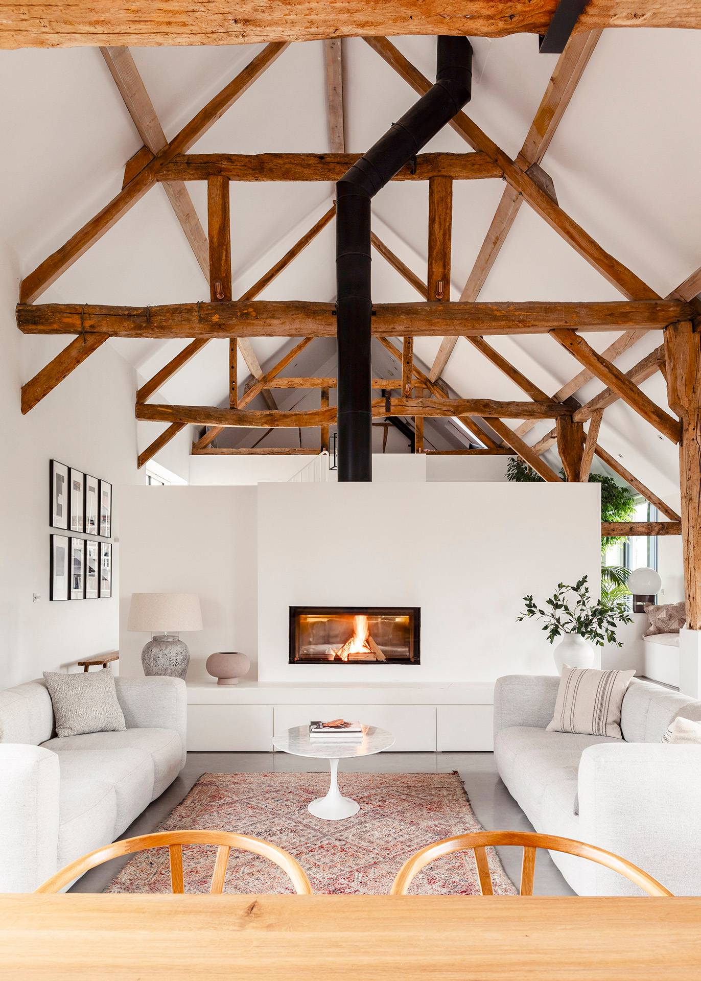 Symmetrical lounge view showing a contemporary inset fireplace set under exposed oak roof trusses in Wiltshire, Love Locations SN8.