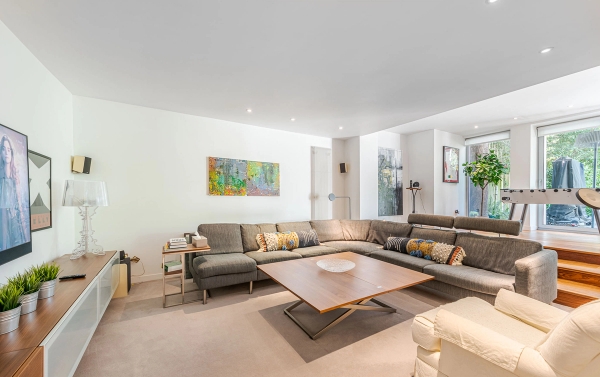 Large contemporary family room layout featuring a deep grey L-shaped sectional sofa and minimalist low-profile table, ideal for cozy home brand ads, Love Locations.