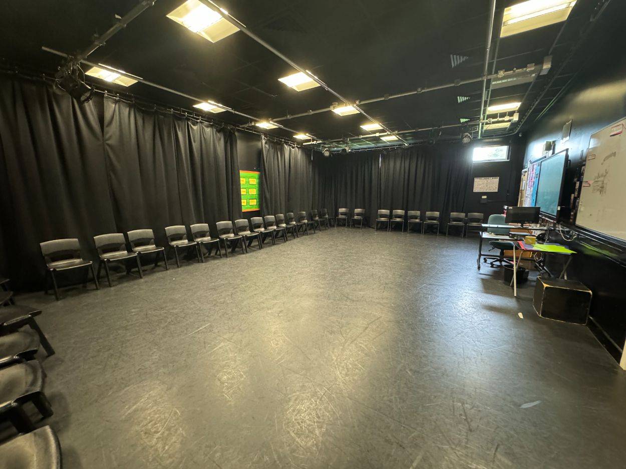 Spacious black box drama classroom photo location surrounded by black drapes and overhead stage lighting via Love Locations.