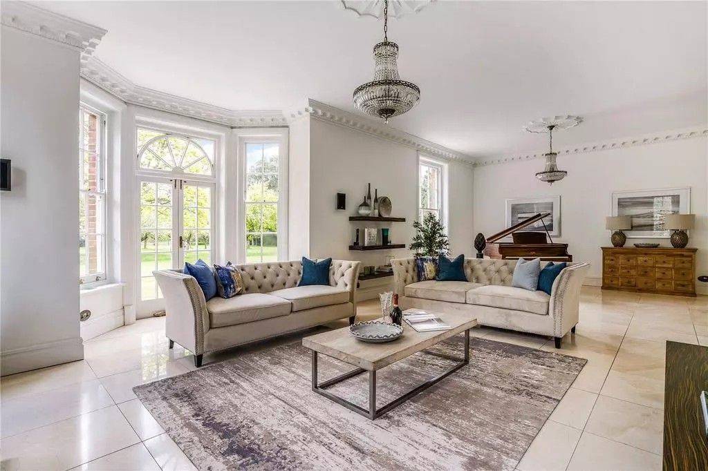 Grand period drawing room shoot space in Reading RG10 via Love Locations, showcasing tall sash bay windows, dual cream sofas, dark wood flooring, and a crystal chandelier.