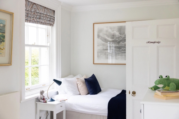 Love Locations classic children's bedroom Steyning West Sussex: Minimalist single bed layout with crisp white linens, navy accents, and window view, ideal for family brand campaigns.