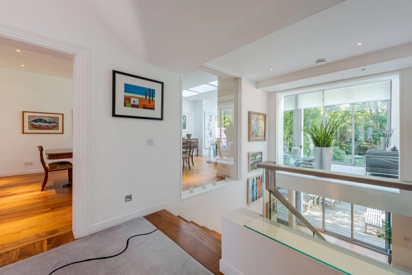 Bright interior landing featuring white walls, glass partitions, and polished wooden floors, perfect for contemporary drama film sets, Love Locations.