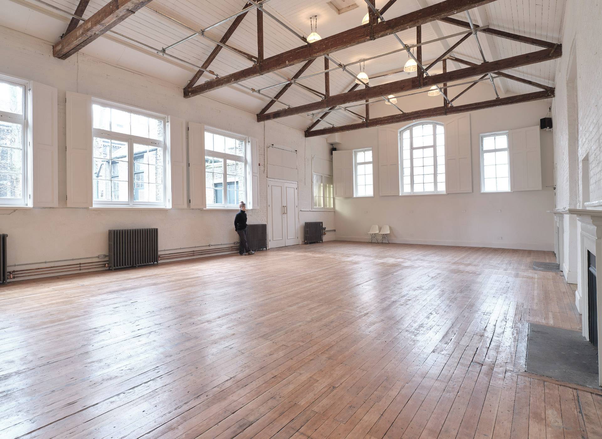 Bright high-ceiling hall space with natural light streaming through windows onto wooden floors, ideal for commercial filming, Love Locations E2.