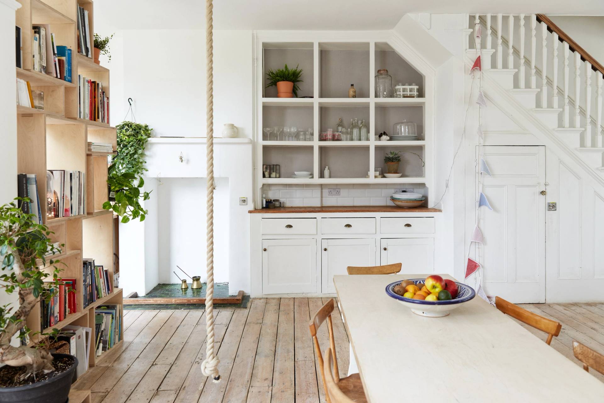 Open-plan dining kitchen transition in Palmers Green, N13 featuring white fitted shelving, period fireplace, and hanging rope detail, Love Locations.