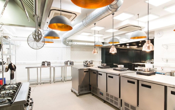Commercial kitchen studio for hire with modern stainless steel prep stations and industrial extraction fans in Old Street, London, EC1V 1JN via Love Locations.