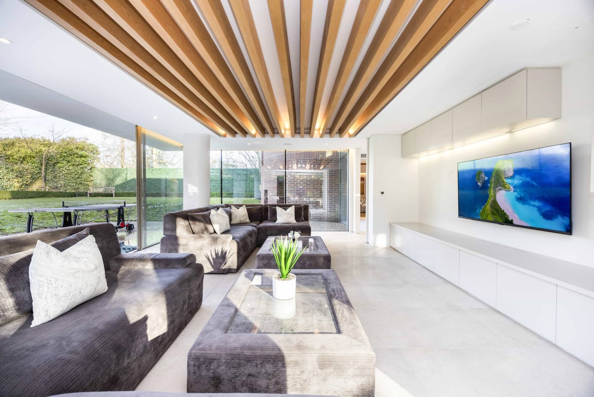 Lounge room view showcasing slatted timber ceiling details, grey velvet seating, and garden light, Love Locations WD7.
