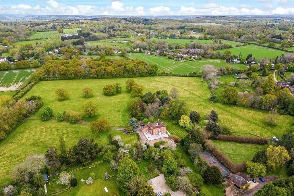 High-angle aerial drone view of the red-brick Georgian country estate and surrounding private green fields in Reading RG10 from Love Locations.