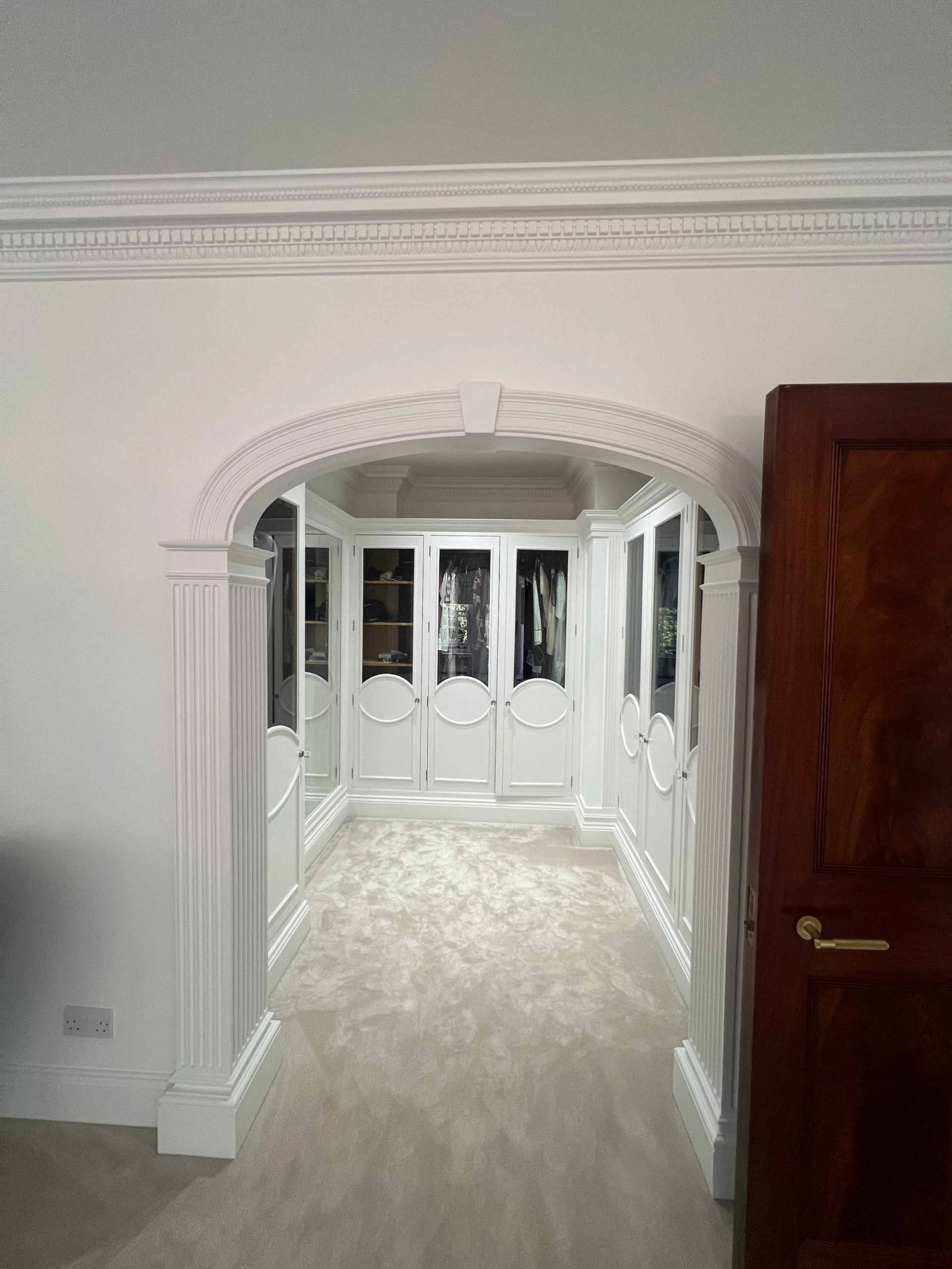 Arched hallway doorway leading into a white panelled dressing room suite, Love Locations BR7.