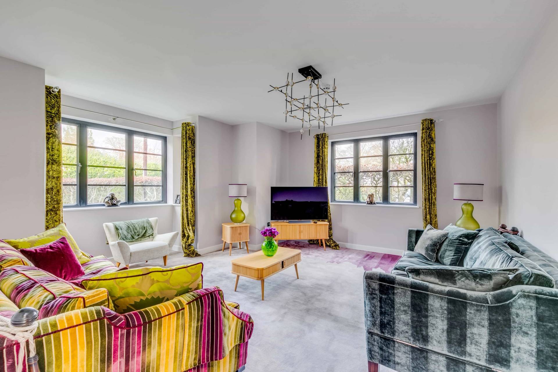 Bright reception room with a striped sofa, gold coffee table, colorful armchairs, and crittall windows, Love Locations CB2.