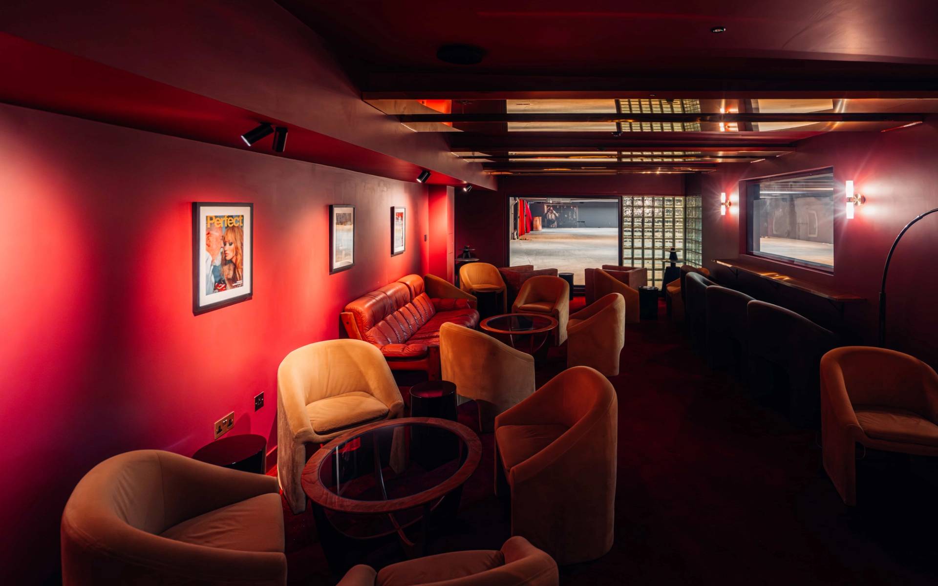 Crimson red velvet bar lounge location house in Brentford TW8 through Love Locations, featuring warm ambient wall sconces and retro armchairs.