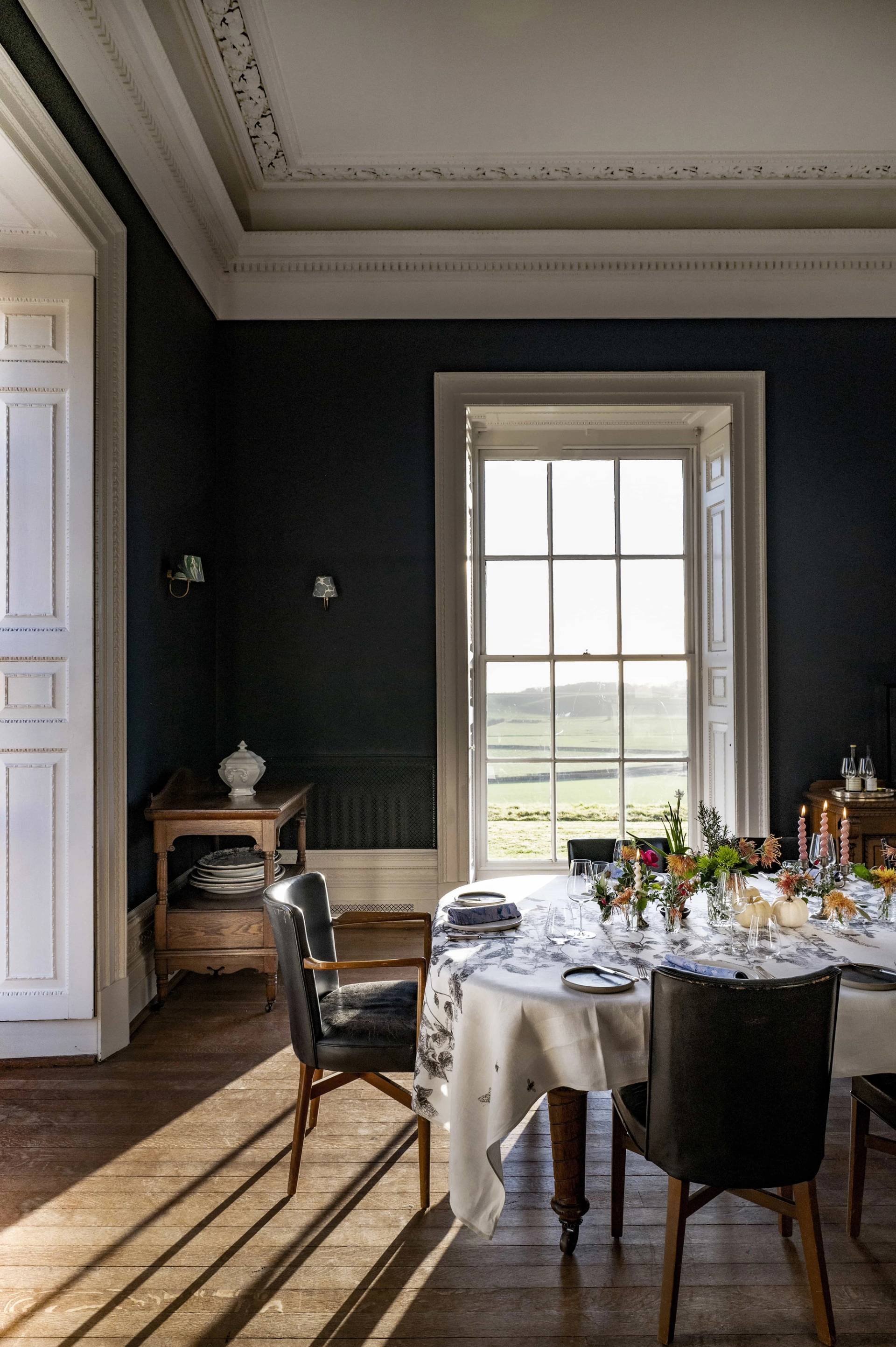 Dining room sash window framing sweeping countryside views beside a dark navy feature wall, perfect for editorial photography, Love Locations LE7.
