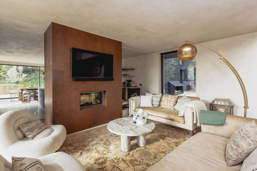Cozy reception lounge featuring a built-in copper fireplace wall, flat screen TV, and soft armchairs, Love Locations GU32.
