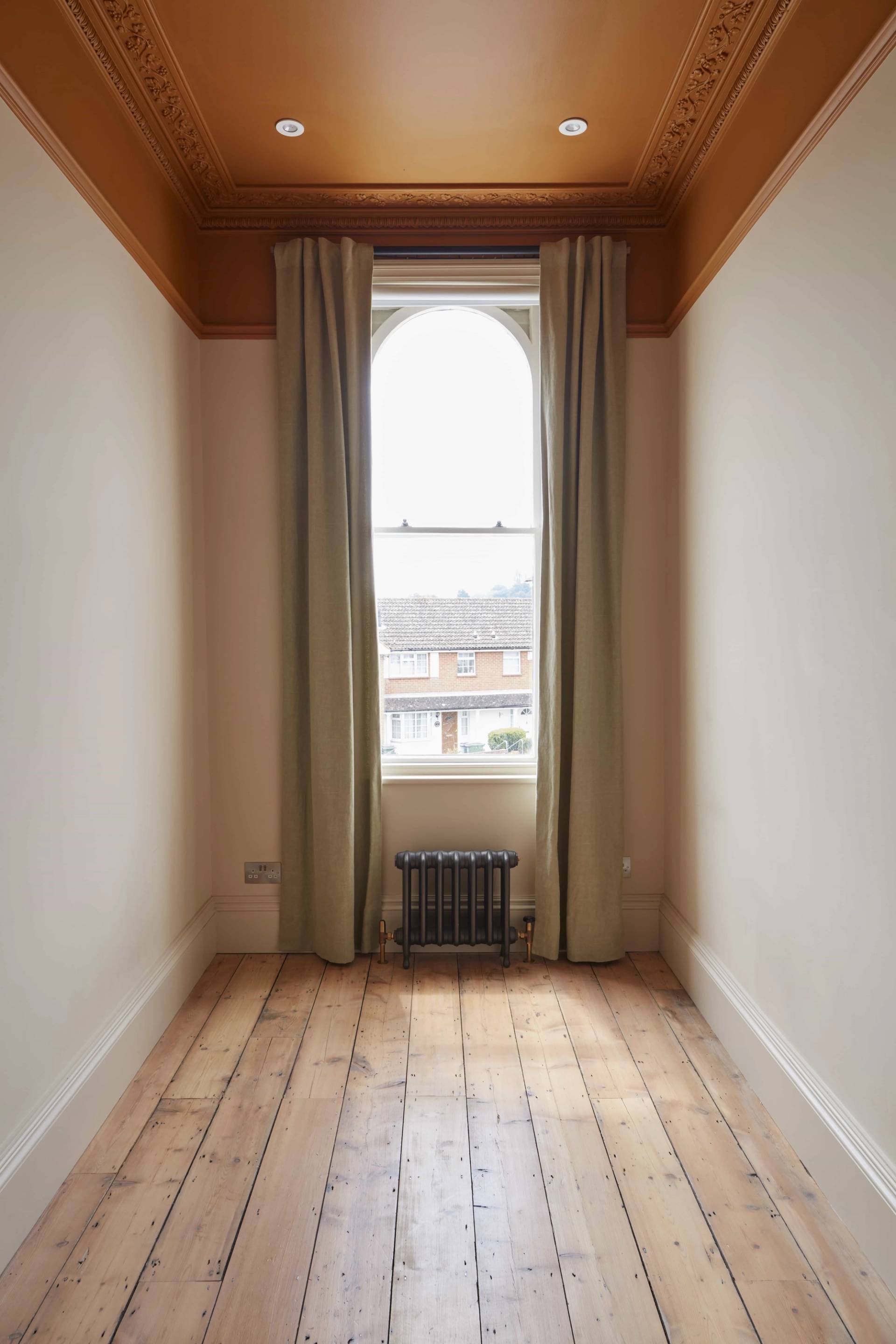 Narrow sash window framed by sage green curtains and stripped wood flooring, Love Locations TN34.