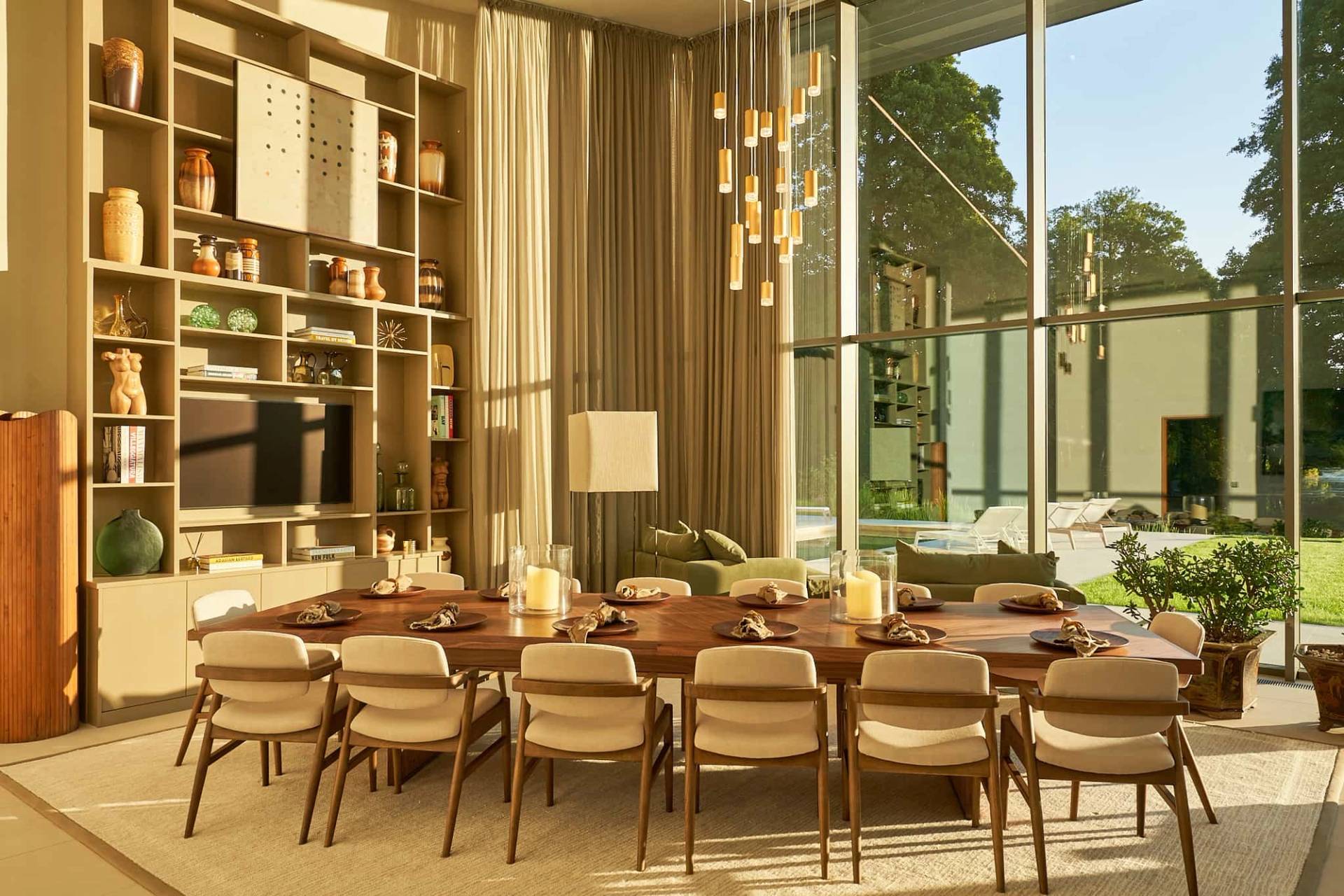 Formal dining area set under brass pendant light fixtures in a modern glass mansion, Love Locations SO21.