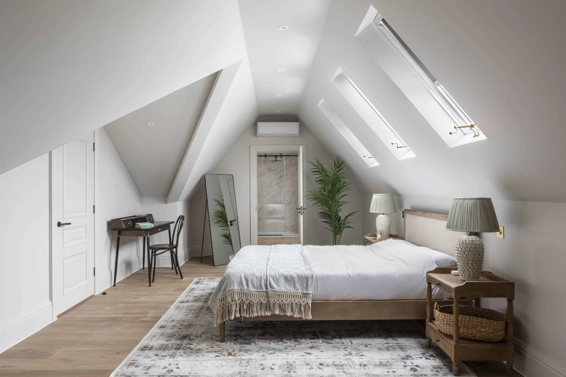 Attic loft bedroom featuring sloped ceilings, skylights, white bed linen, and neutral area rug, Love Locations HP18.