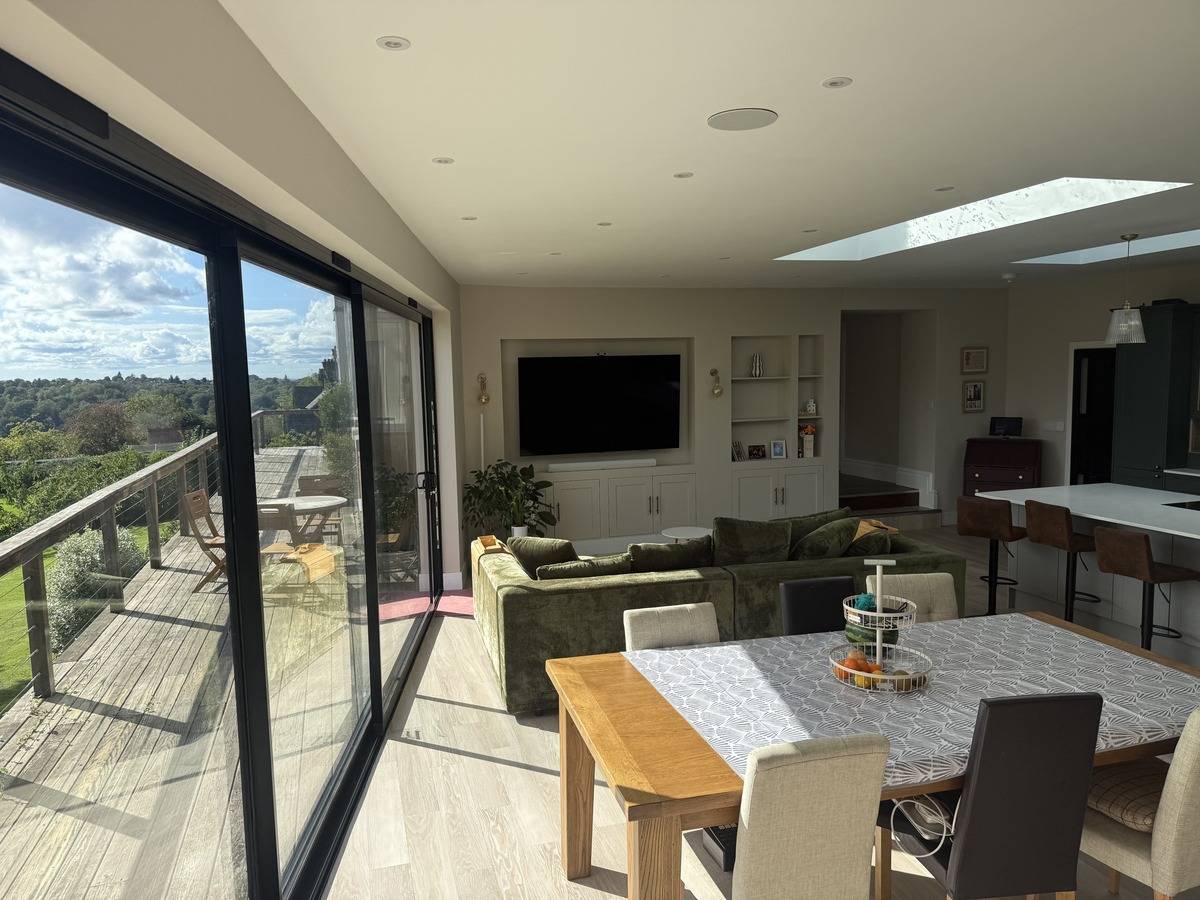 Open-plan living and dining space for media production in Stockport SK6 by Love Locations, displaying black sliding patio doors and modern dining table.