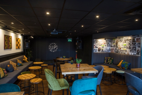 Upstairs event space and bar venue layout showcasing 'Upstairs at the Ritzy' wall branding, wooden tables, and colorful seating, ideal for live music video sets, Love Locations SW2.