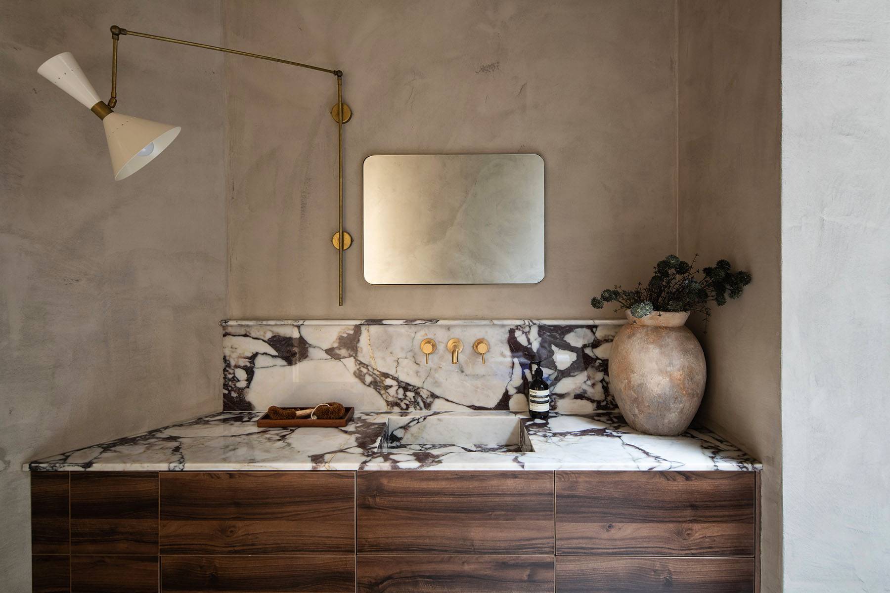 Sunk-in bathtub set under a skylight with dark-veined marble splashback and micro-cement walls, ideal for luxury wellness shoots, Love Locations SW16.