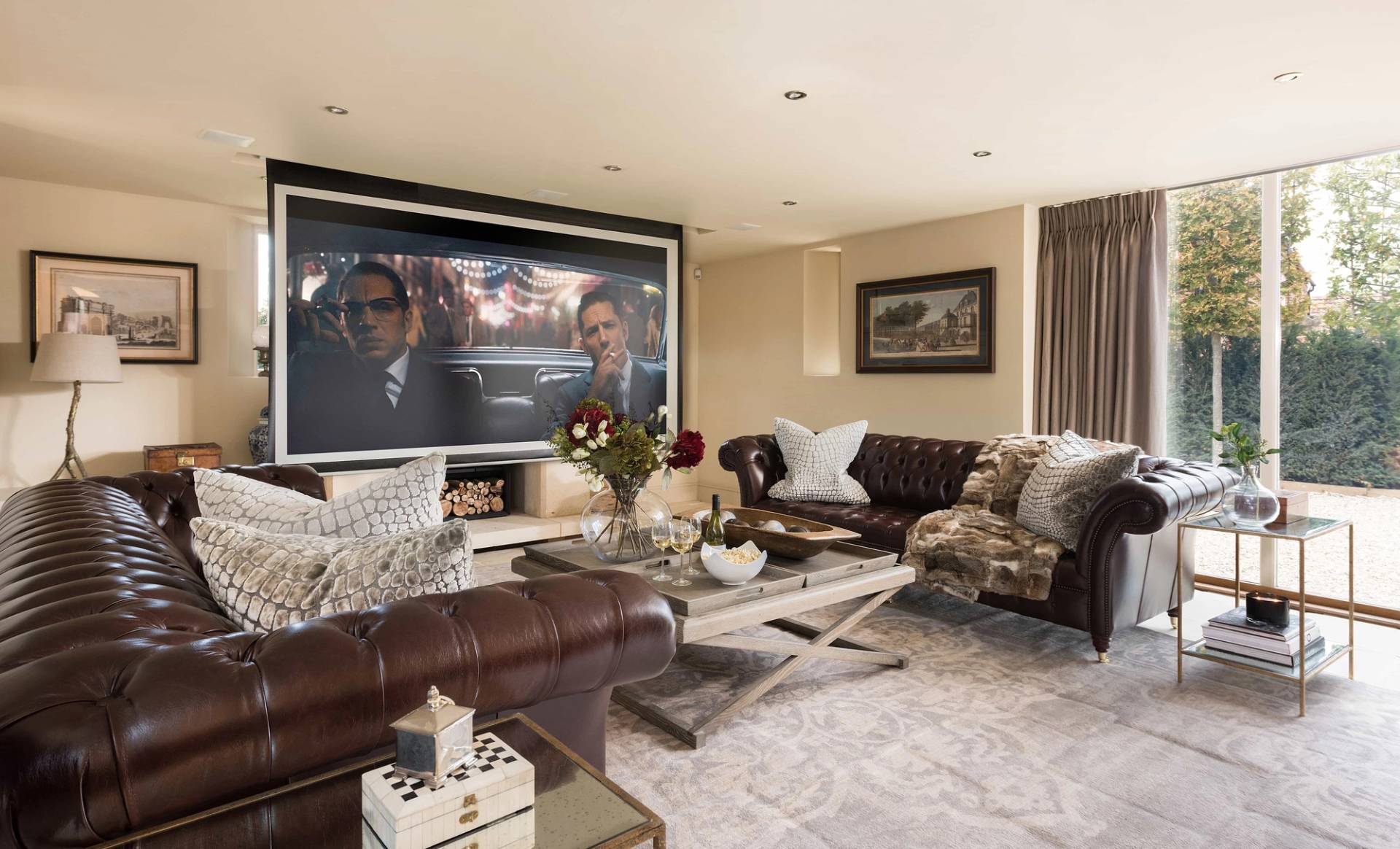 Luxury home cinema room and media lounge film location in Cheltenham GL51 from Love Locations, featuring deep brown leather Chesterfield sofas and a large projection screen.