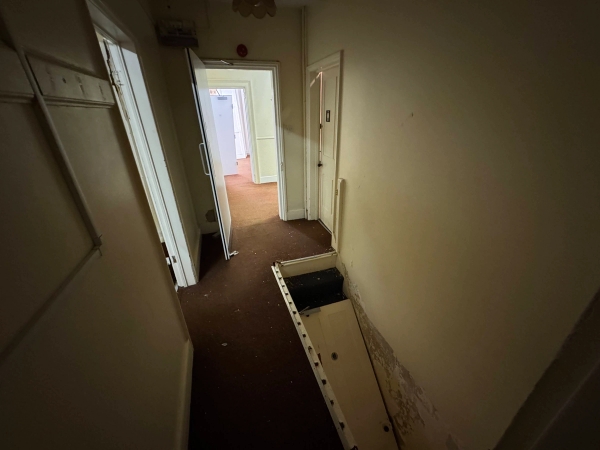 Multi-level institutional hallway view looking down a stairwell with stained brown carpets, Love Locations Beeston.