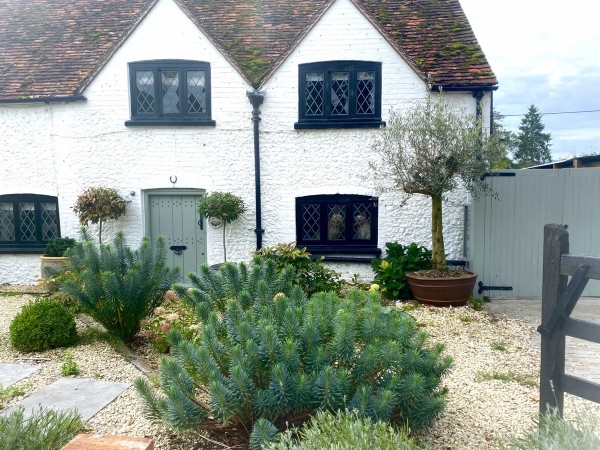 Traditional Tudor cottage exterior facade in RG9 6QD featuring black timber framing, white-rendered walls, and black leaded windows, ideal for period drama filming via Love Locations.