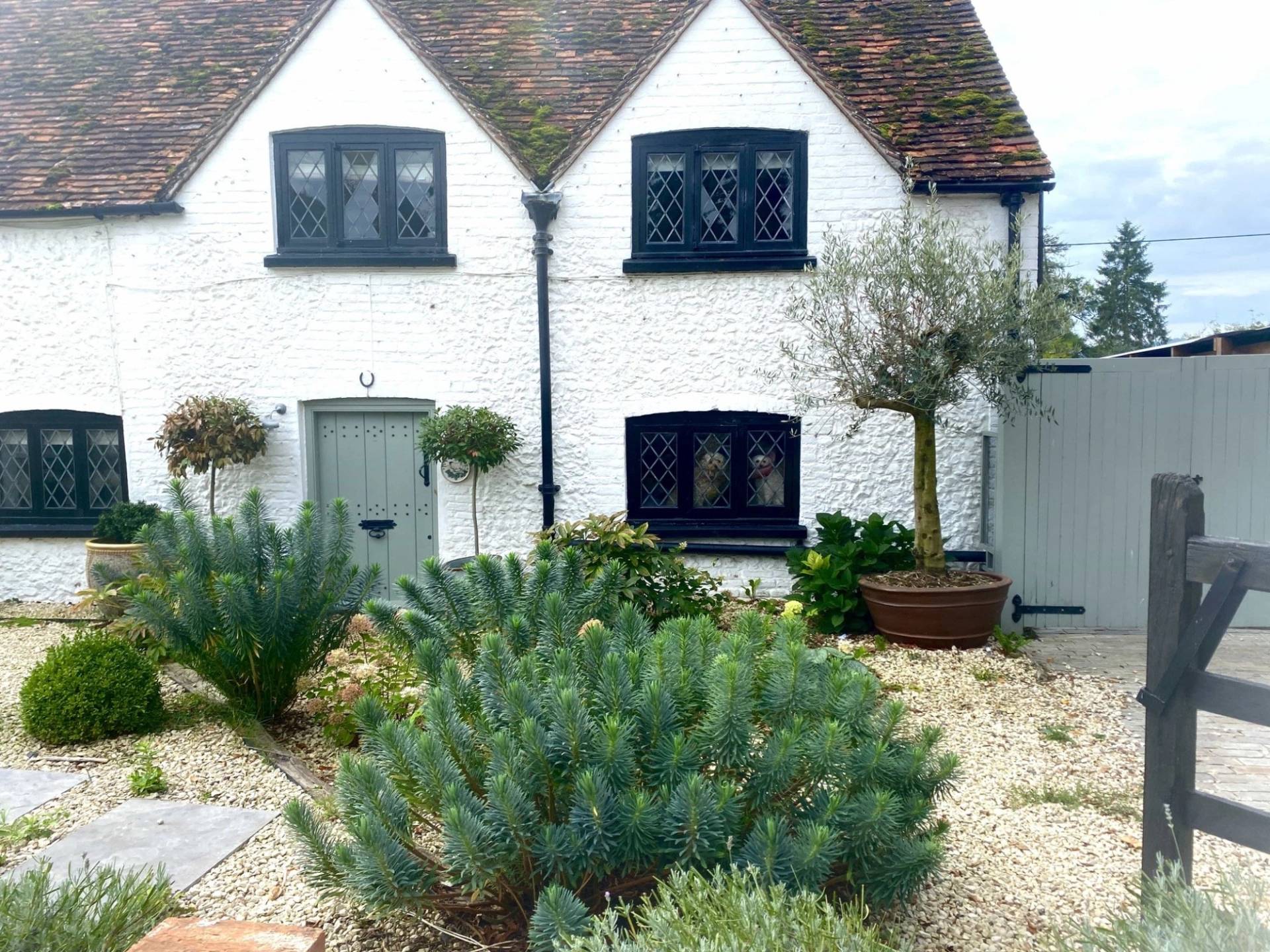 Traditional Tudor cottage exterior facade in RG9 6QD featuring black timber framing, white-rendered walls, and black leaded windows, ideal for period drama filming via Love Locations.