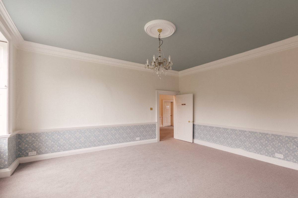 Corner perspective of a light grey bedroom with double sash windows and period white panelled doors, Love Locations SE15.