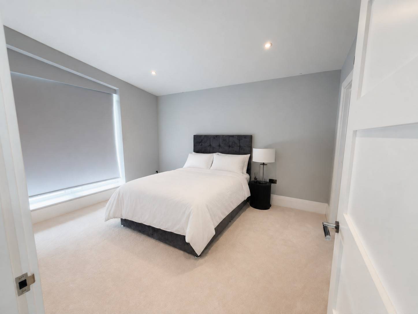 Neutral guest bedroom photoshoot location in Barnet EN4 by Love Locations, displaying a grey upholstered headboard, clean white walls, and soft lighting.