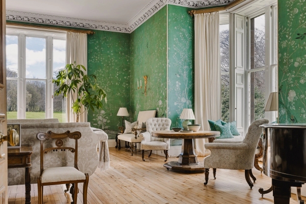 Sunlit castle reception room featuring green patterned walls, wood flooring, and vintage seating, Love Locations KY15.
