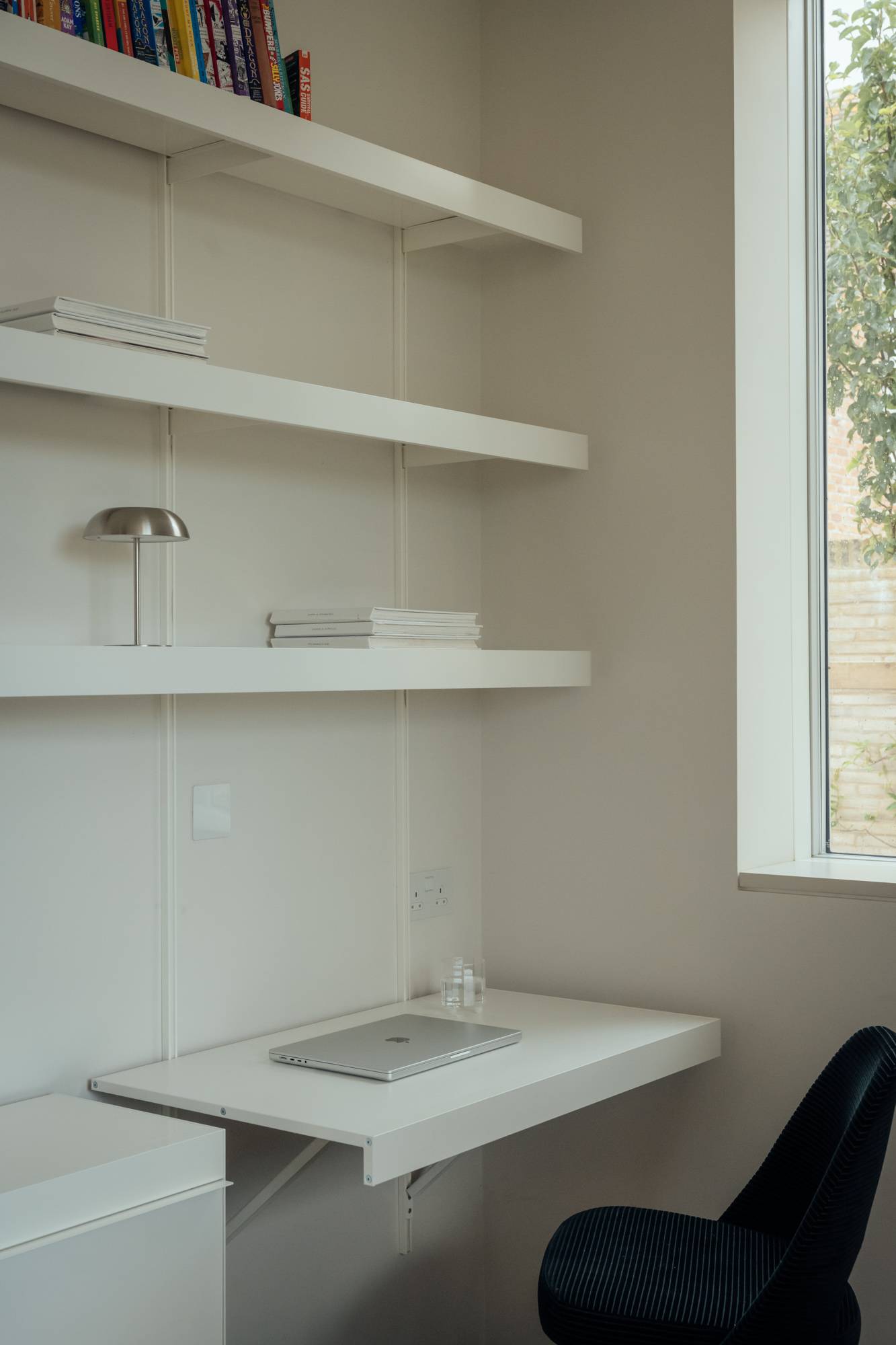 Minimalist utility or study nook with clean white floating shelves and a built-in workspace, Love Locations.