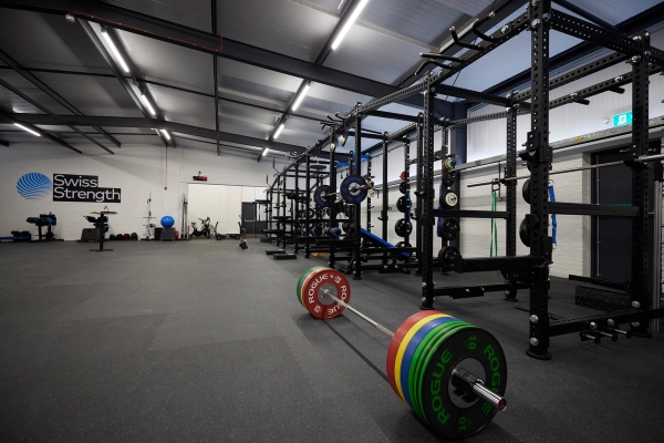 Modern commercial gym shoot location in Winchester, SO23 featuring professional squat racks, bumper weight plates, and a loaded barbell, ideal for fitness brand campaigns via Love Locations.