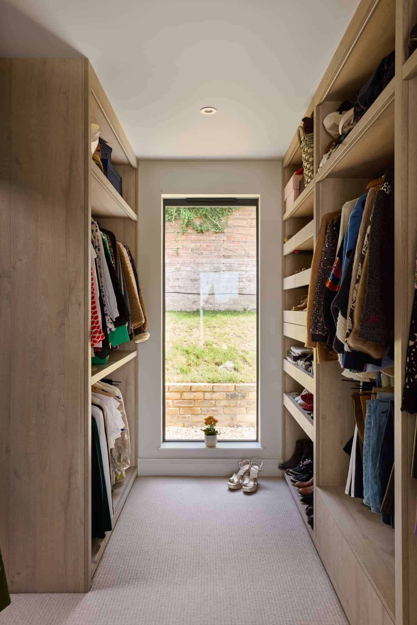 Custom timber walk-in closet dressing room with built-in open shelving and a central slim window, ideal for luxury fashion campaigns, Love Locations KT22.