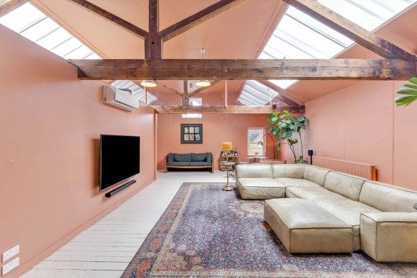 Chic retro living room studio with terracotta pink walls, exposed timber beams, and skylight windows, Love Locations venue.