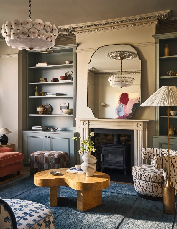 Period fireplace hearth with wood-burning stove, arched wall mirror, grey alcove cabinets, and blue rug, Love Locations SE21.