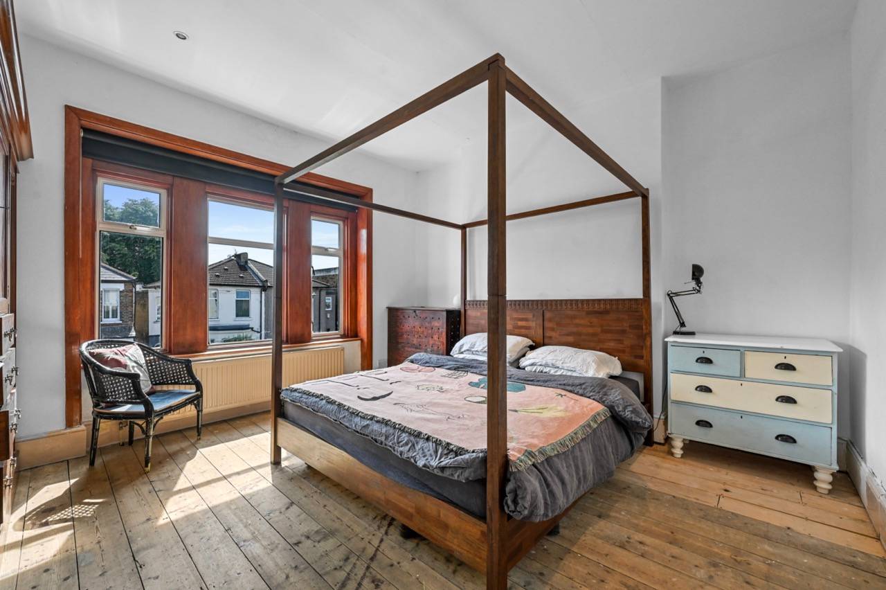 Spacious bedroom featuring a wooden four-poster bed frame, bay windows, and stripped timber floorboards, ideal for bedding lookbooks, Love Locations E7.