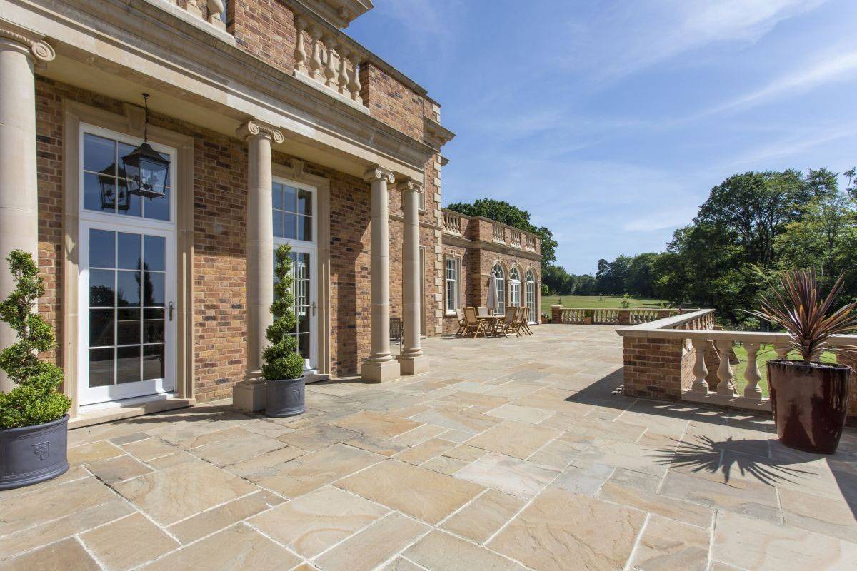 Classical stone pillars and grand French doors leading onto the estate terrace, an elegant editorial backdrop by Love Locations.