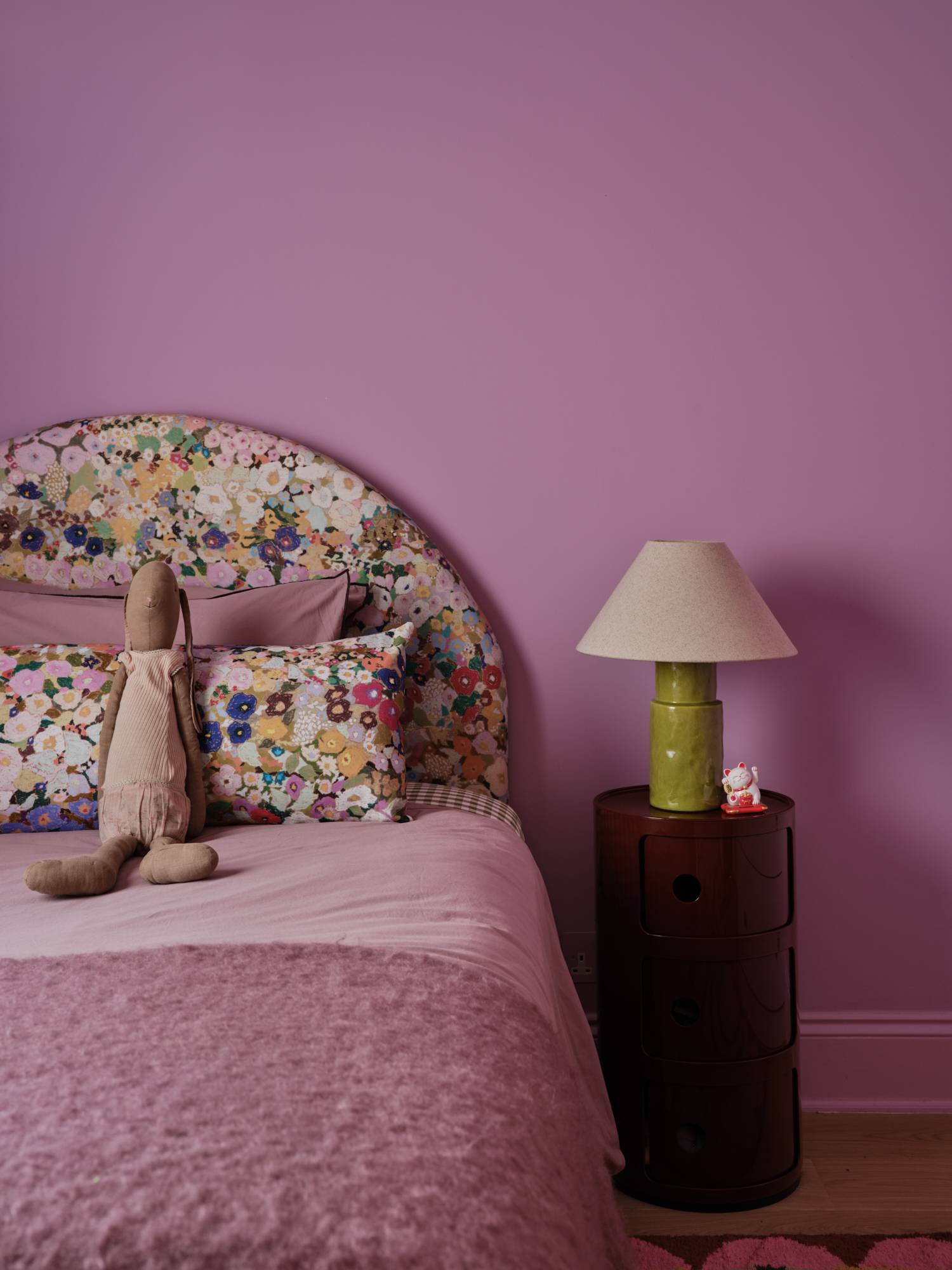 Love Locations lilac children's bedroom shoot location Lewisham SE23: Whimsical bedroom featuring deep lilac walls, a vintage floral patterned arch headboard, and retro lamps, perfect for youth brand ads.