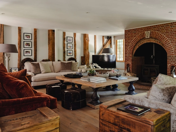 Warm living room lounge with low-beamed ceilings, plush velvet armchairs, and a central timber trunk coffee table, suitable for cozy home brand ads, Love Locations RG9.