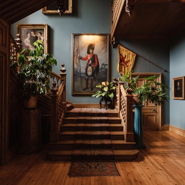 Grand wooden staircase hall with period portraits and blue painted walls in a Scottish castle, Love Locations KY15.