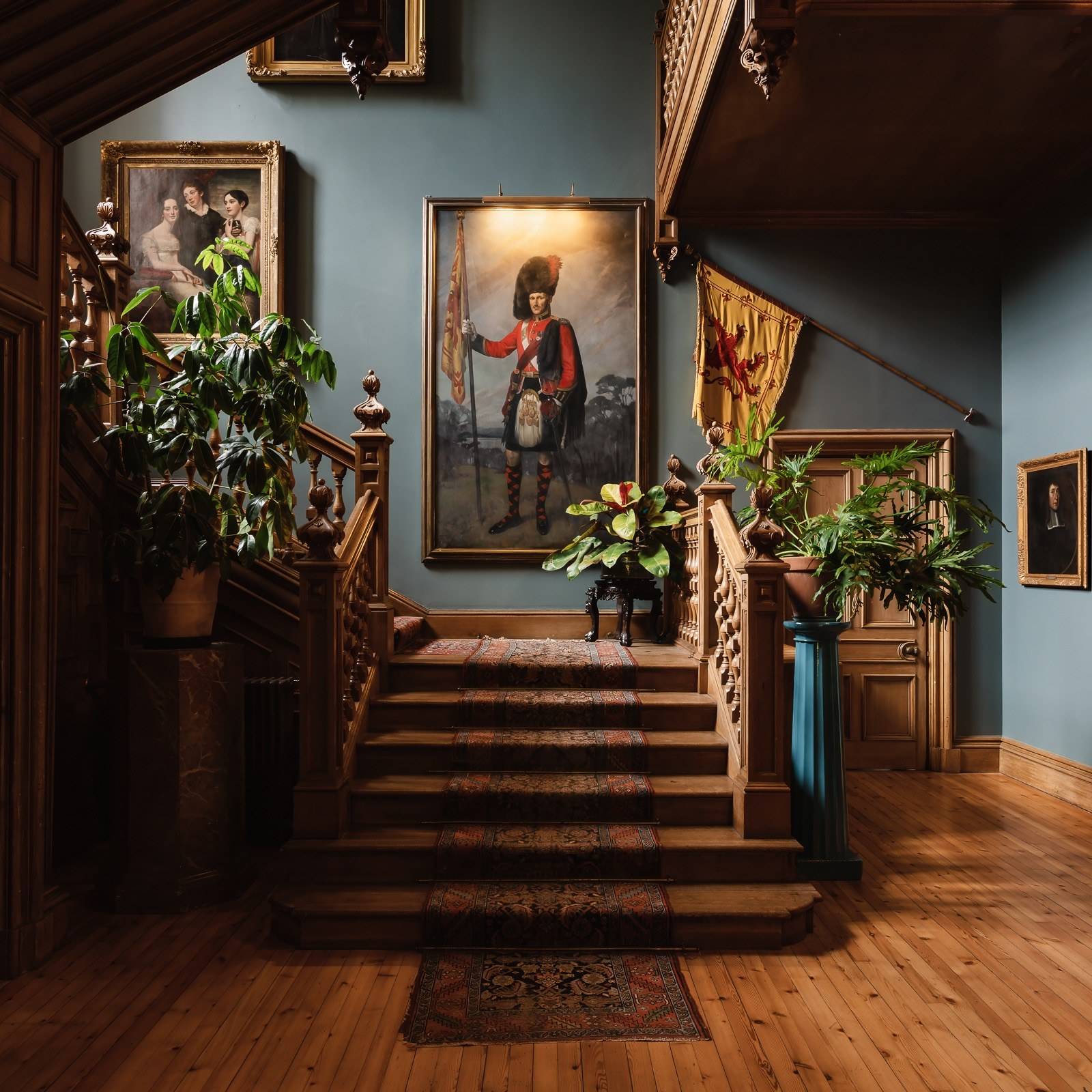 Grand wooden staircase hall with period portraits and blue painted walls in a Scottish castle, Love Locations KY15.