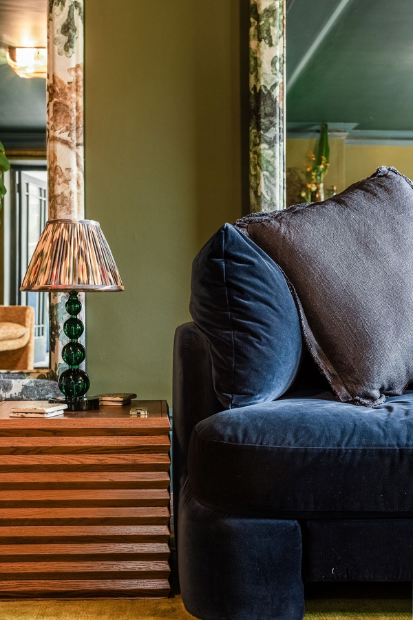 Moody country house corner view with a plush dark velvet sofa and a vintage fringed table lamp, available for media hire through Love Locations.
