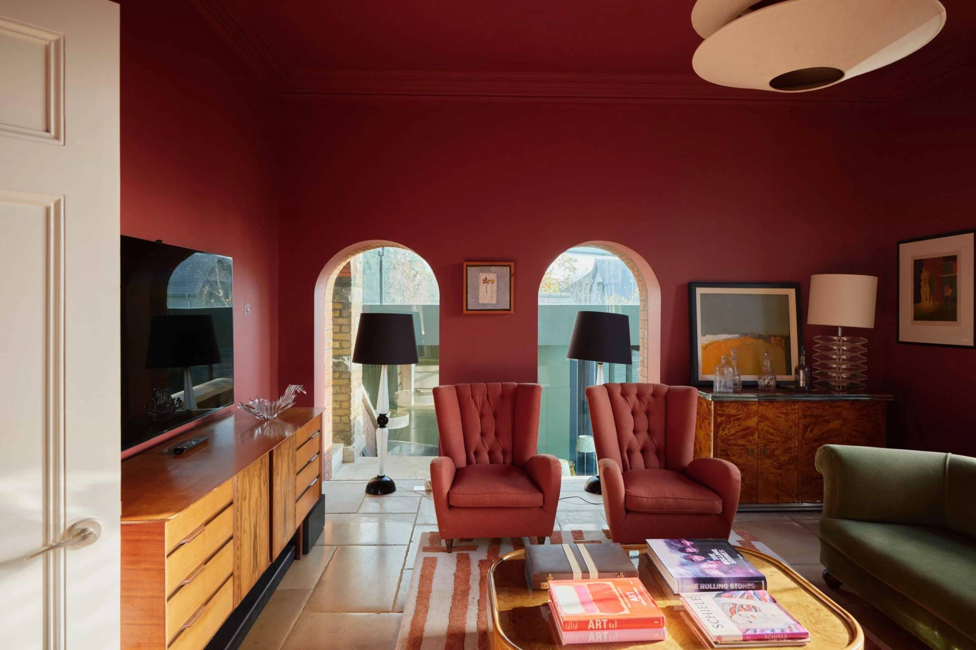 Dramatic dark red cinema or TV room featuring deep orange velvet armchairs and striped carpets, ideal for luxury tech brand ads, Love Locations SW20.