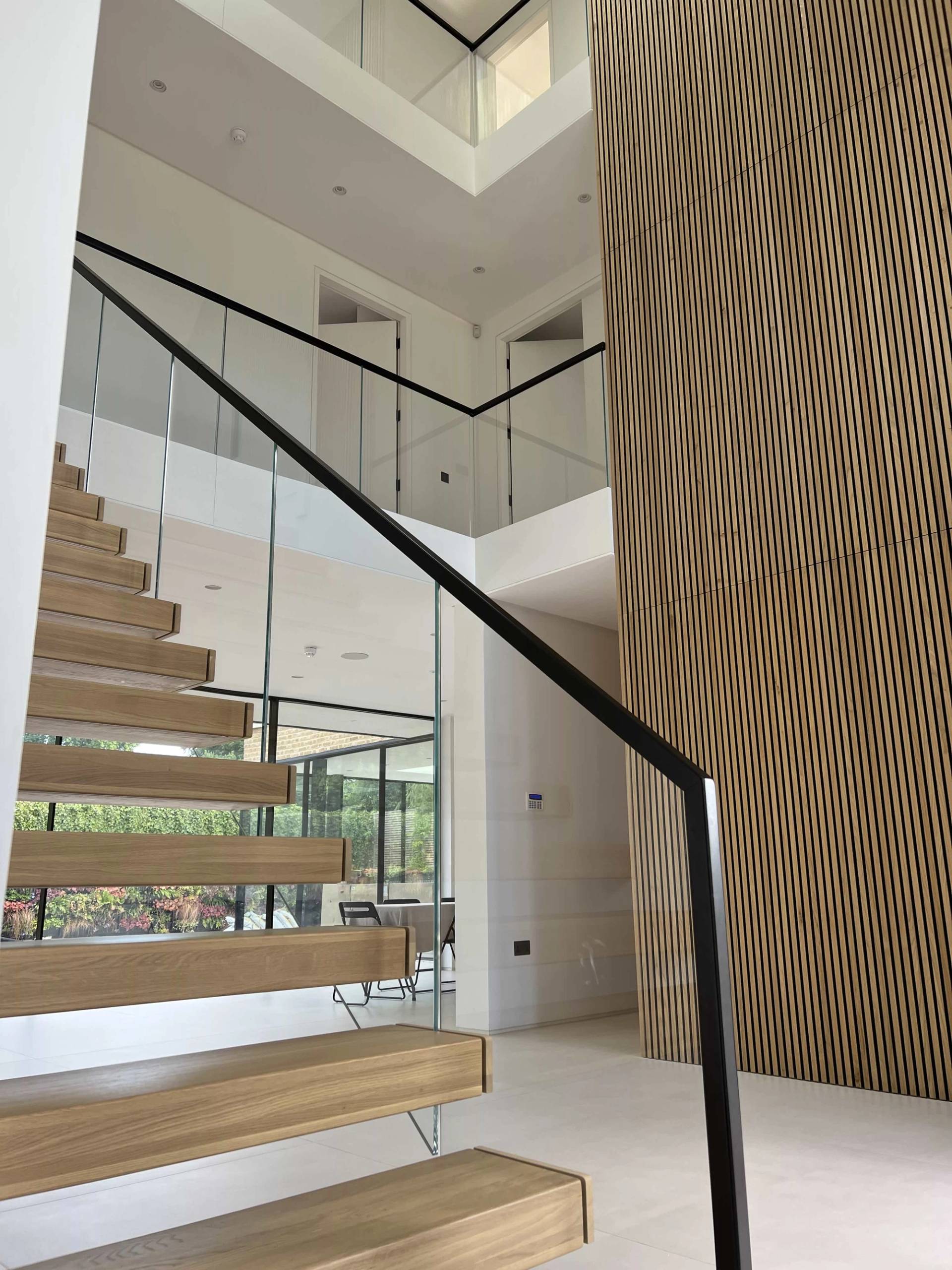 Architectural perspective of a floating wooden stairwell with black handrails and slatted timber feature wall cladding, Love Locations N3.