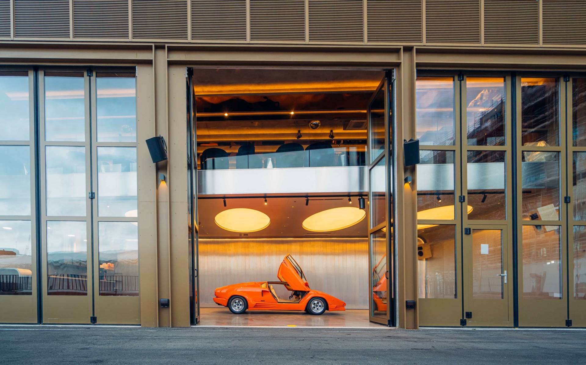 Bright street-level entrance view into a supercar listening bar filming venue in Brentford TW8 from Love Locations, featuring an orange Lambo.