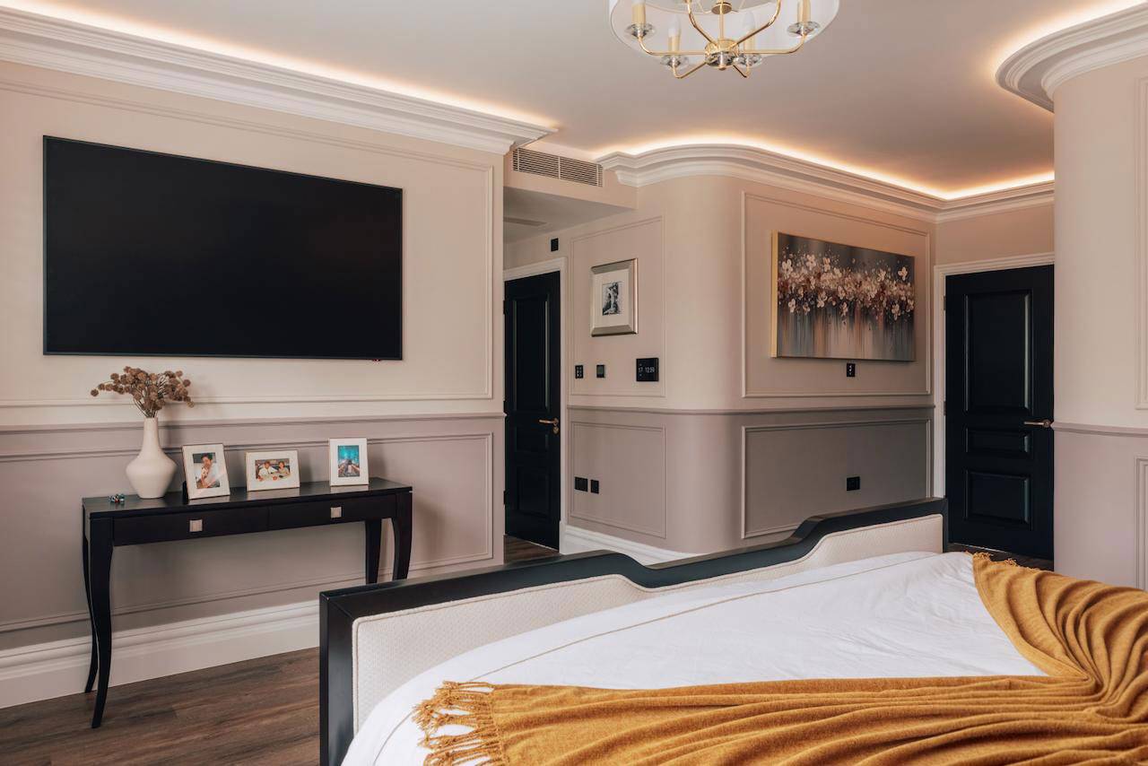 Master bedroom media wall setup with built-in TV, black doors, and warm cove lighting, Love Locations W5.